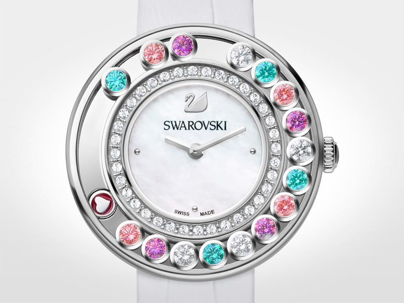 Este reloj divertido y femenino incorpora elementos flotantes que se mueven alrededor de la esfera en sentido circular. Tiene caja de 35 mm de acero con 16 Swarovski Cubic Zirconias móviles en rosa, púrpura, blanco y verde menta; la esfera es de madreperla con logotipo del cisne a las 12; correa de 18,5 cm de piel de becerro con diseño de cocodrilo y hebilla de acero; cuarzo.